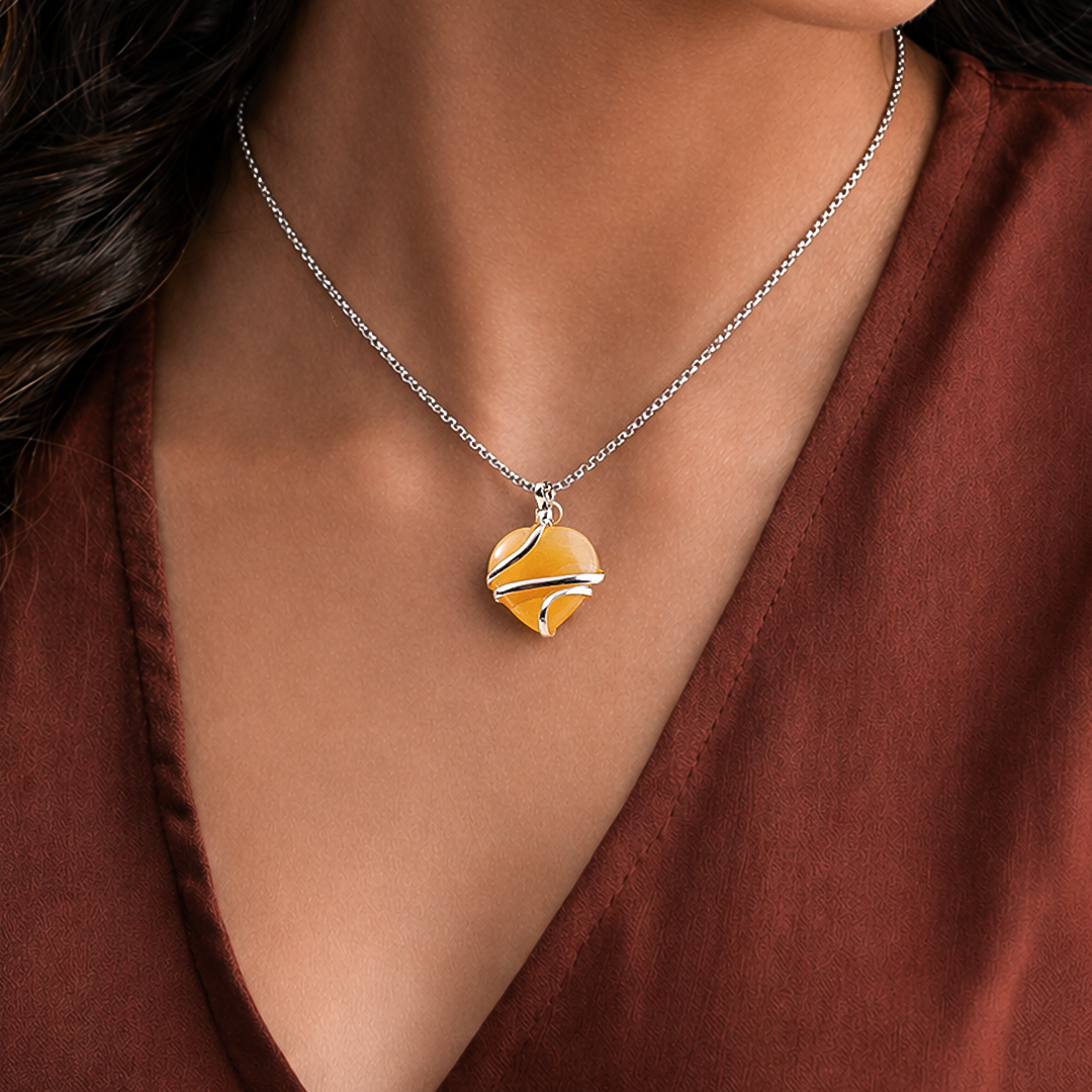 Necklace with a yellow and orange pendant worn by a person in a brown top.