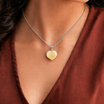 Heart-shaped pendant necklace on a person wearing a rust-colored top