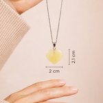 Heart-shaped pendant necklace with measurements on a beige background
