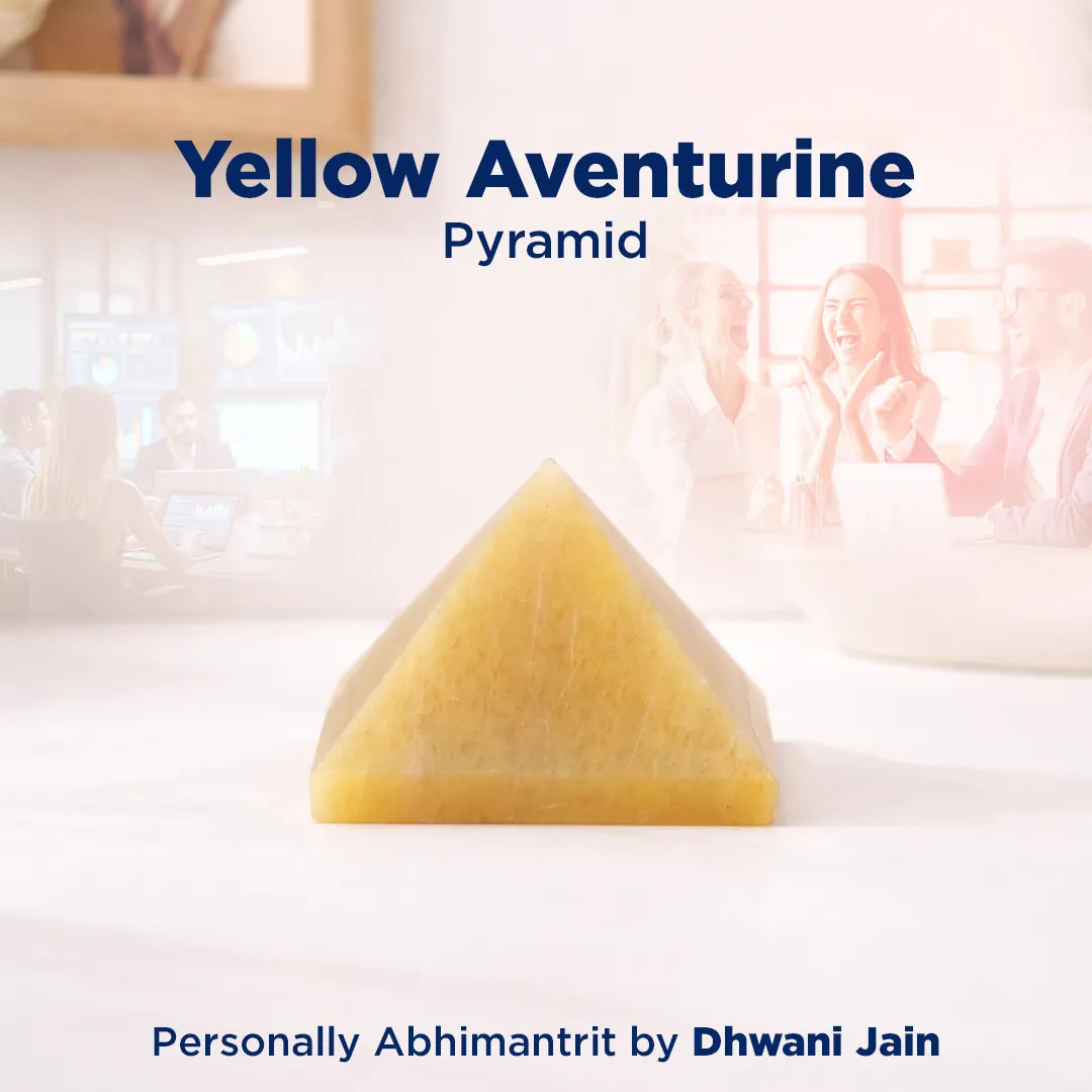 Yellow aventurine pyramid on a white surface with a blurred background