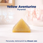 Yellow aventurine pyramid on a white surface with a blurred background