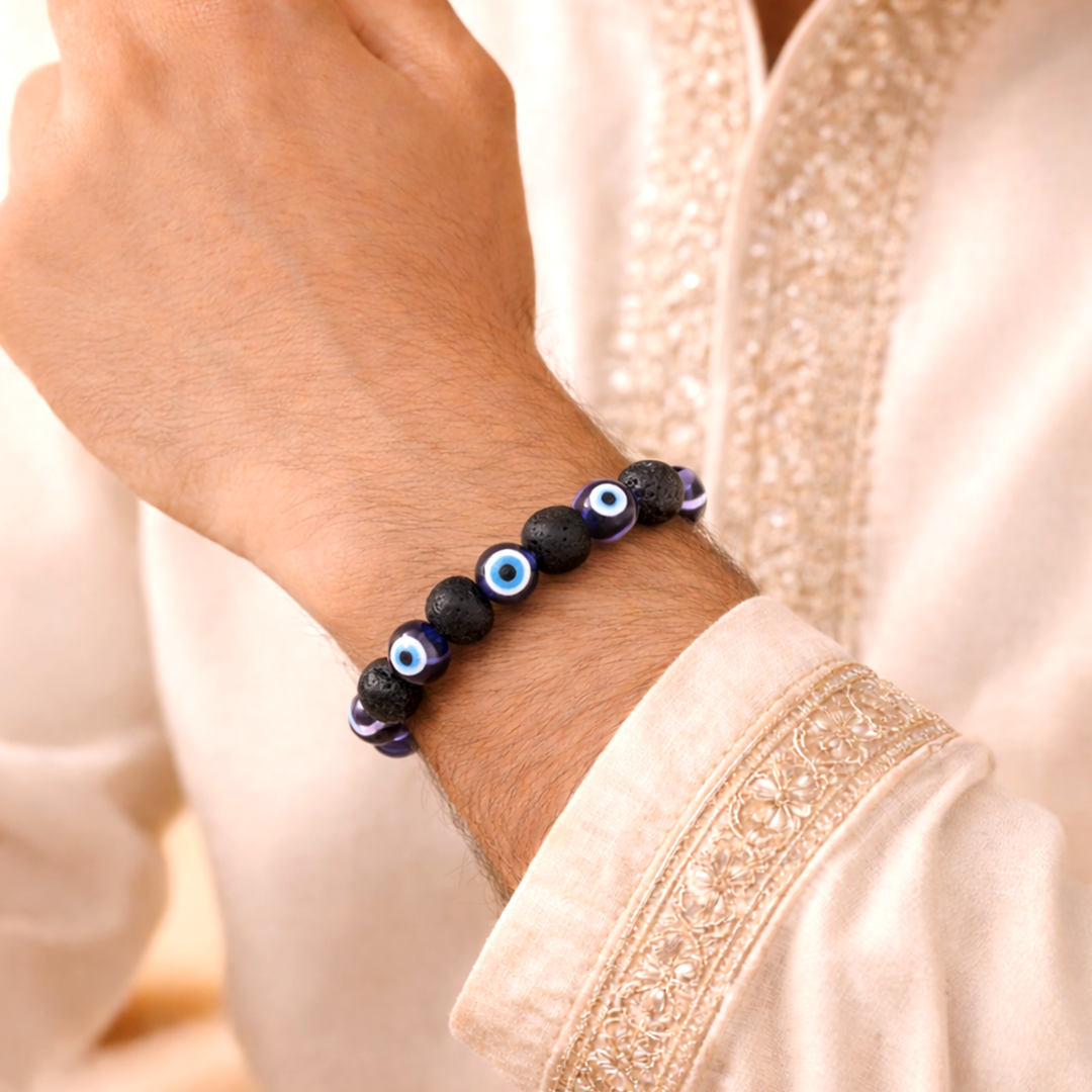 Black beaded bracelet with blue eye beads on a wrist, wearing a light pink garment.