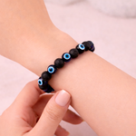 Black beaded bracelet with blue eyes on a wrist against a light background